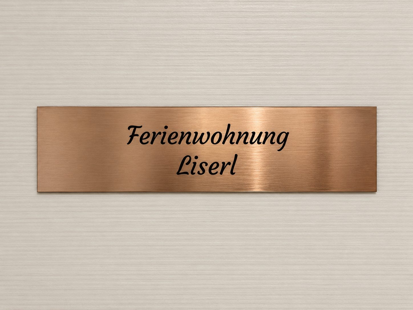 Kupfernes Namensschild mit der Aufschrift Ferienwohnung Liserl an der Wohnungstür